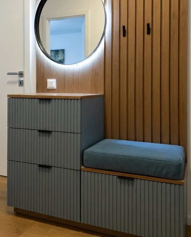 A modern, open-concept living space with a wooden table, chairs, and a metal staircase. The room is lit by ceiling lights and natural sunlight from large windows.